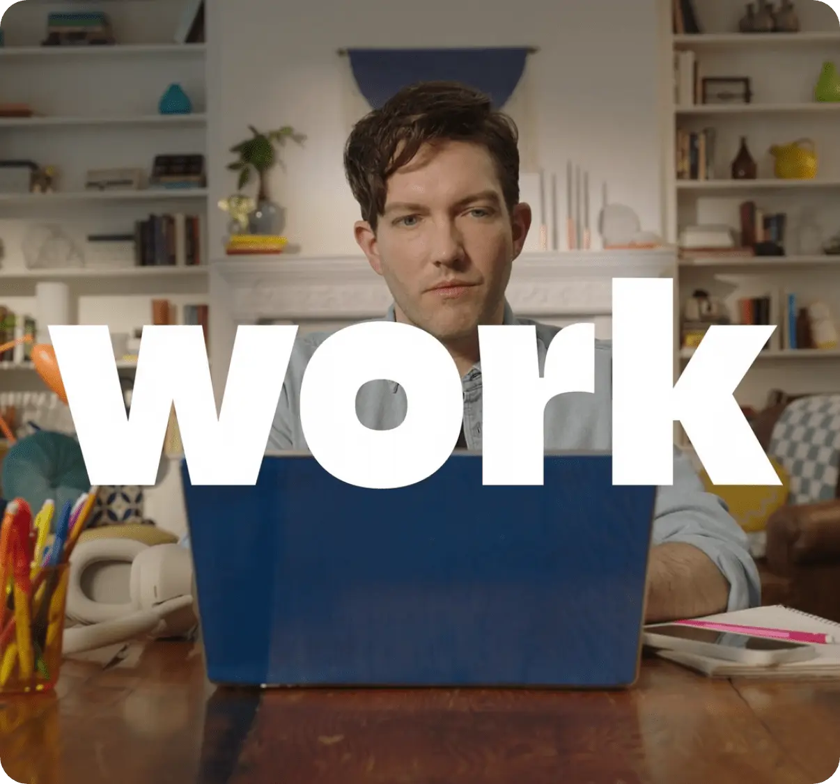 Man looks down at his laptop in a home workspace with the word work superimposed over him.